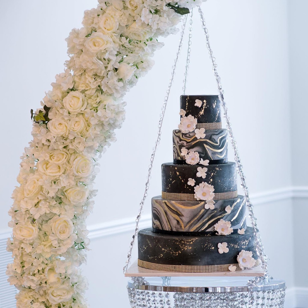 white floral arch over wedding cake